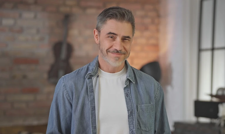 Portrait of happy casual middle aged man standing at home in loft living room